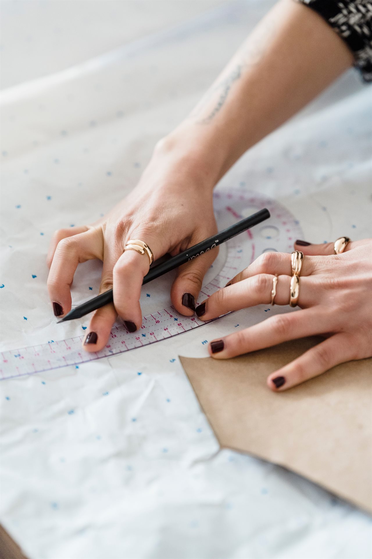 Dressmaker working on a paper sewing pattern with a ruler