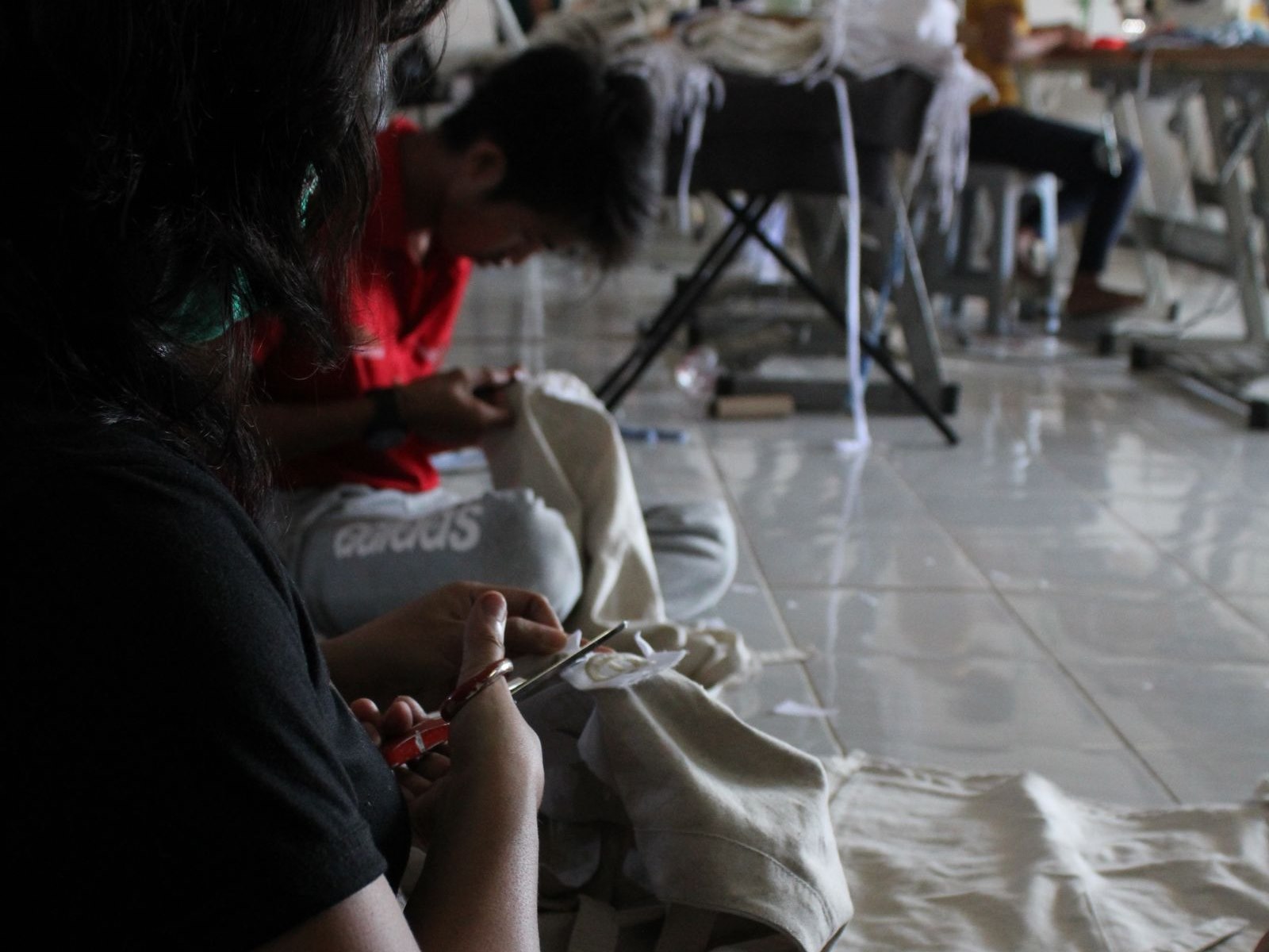 Garment workers trimming and sewing pieces in a production workshop