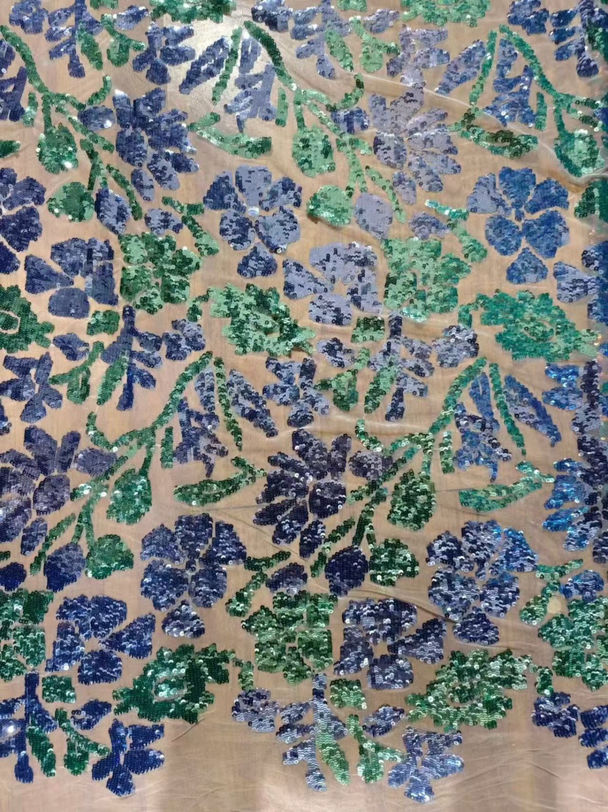 Blue and green floral sequin motifs on a light open fabric ground
