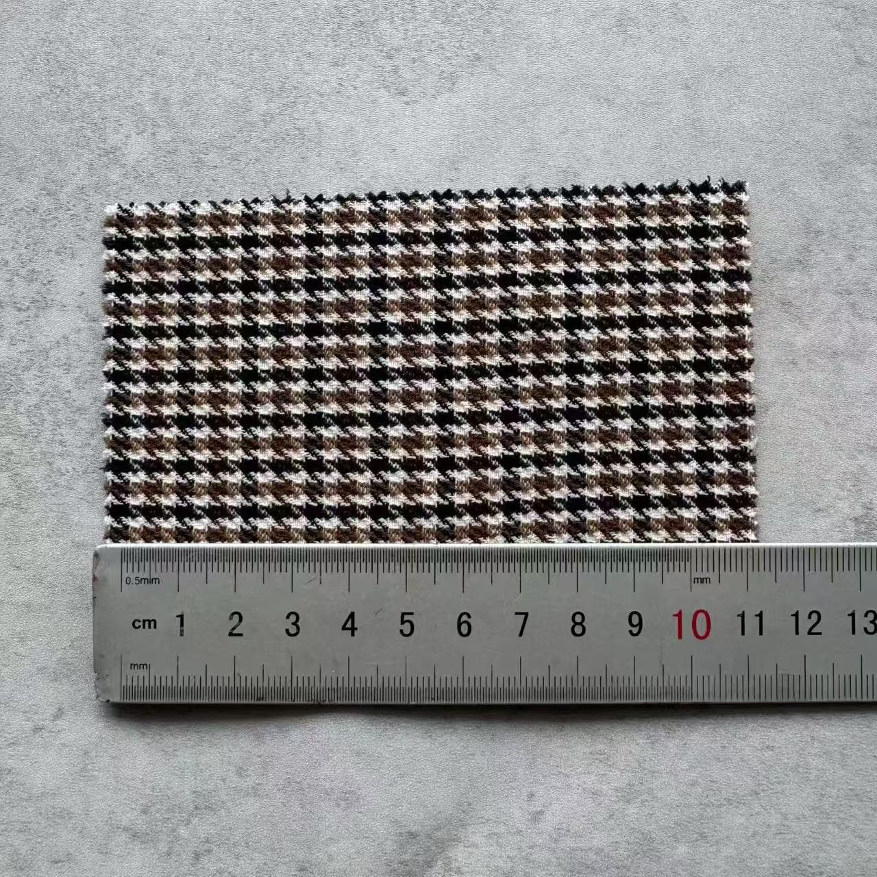 Brown, cream and dark houndstooth fabric swatch next to a ruler
