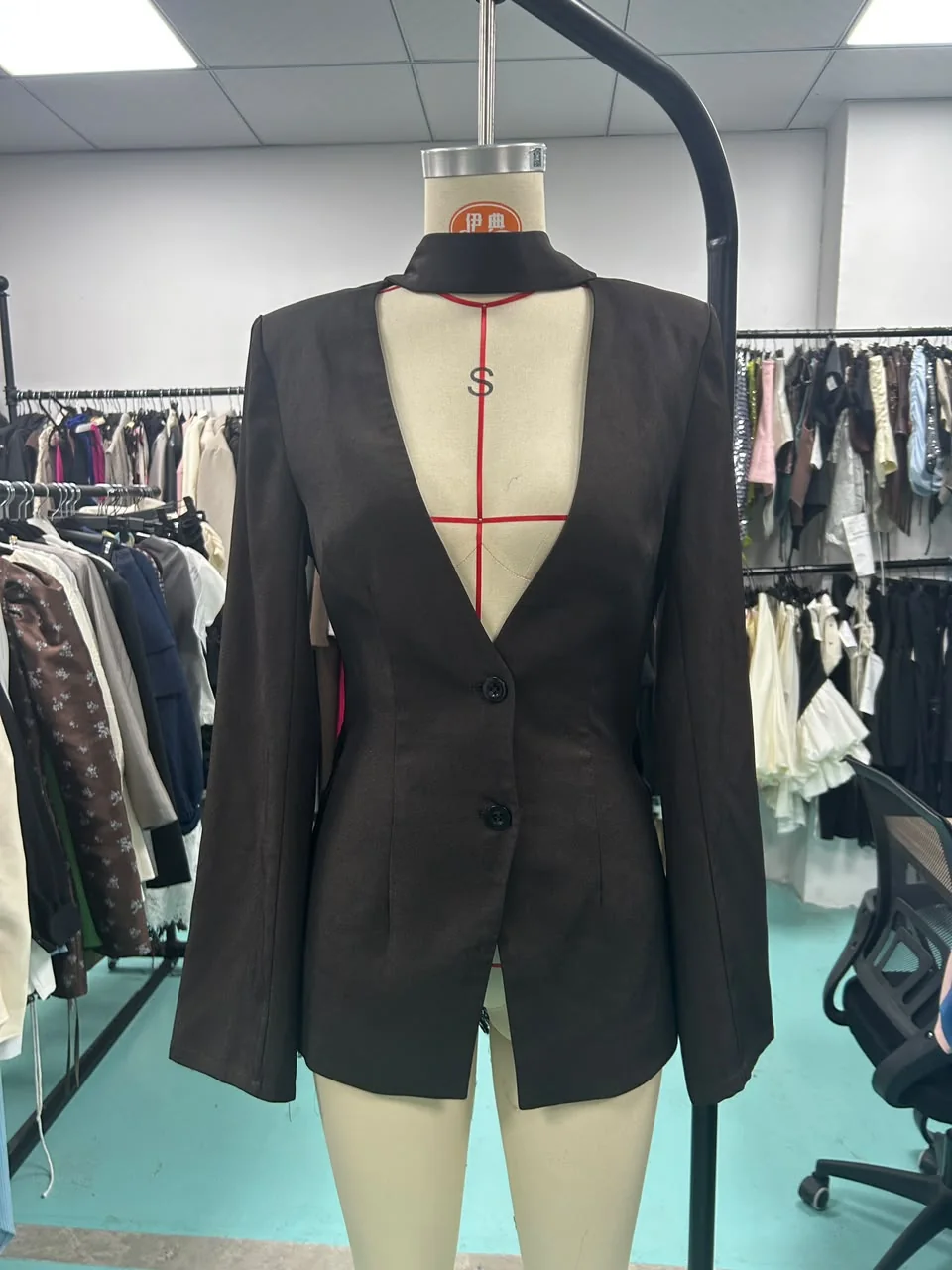 Dark tailored blazer with a deep front cut-out, photographed on a mannequin in the workspace